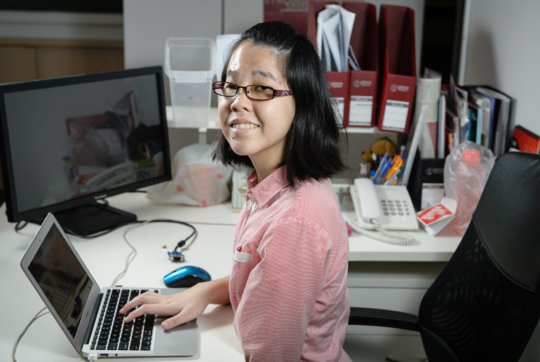 A young female employee smiling for a photo while going about her daily work tasks