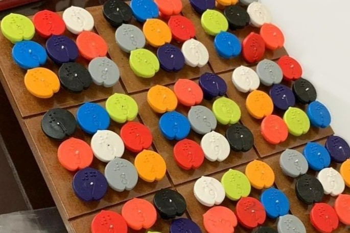 A completed Sudoku board with colour-coded pegs placed on a 9-by-9 grid.