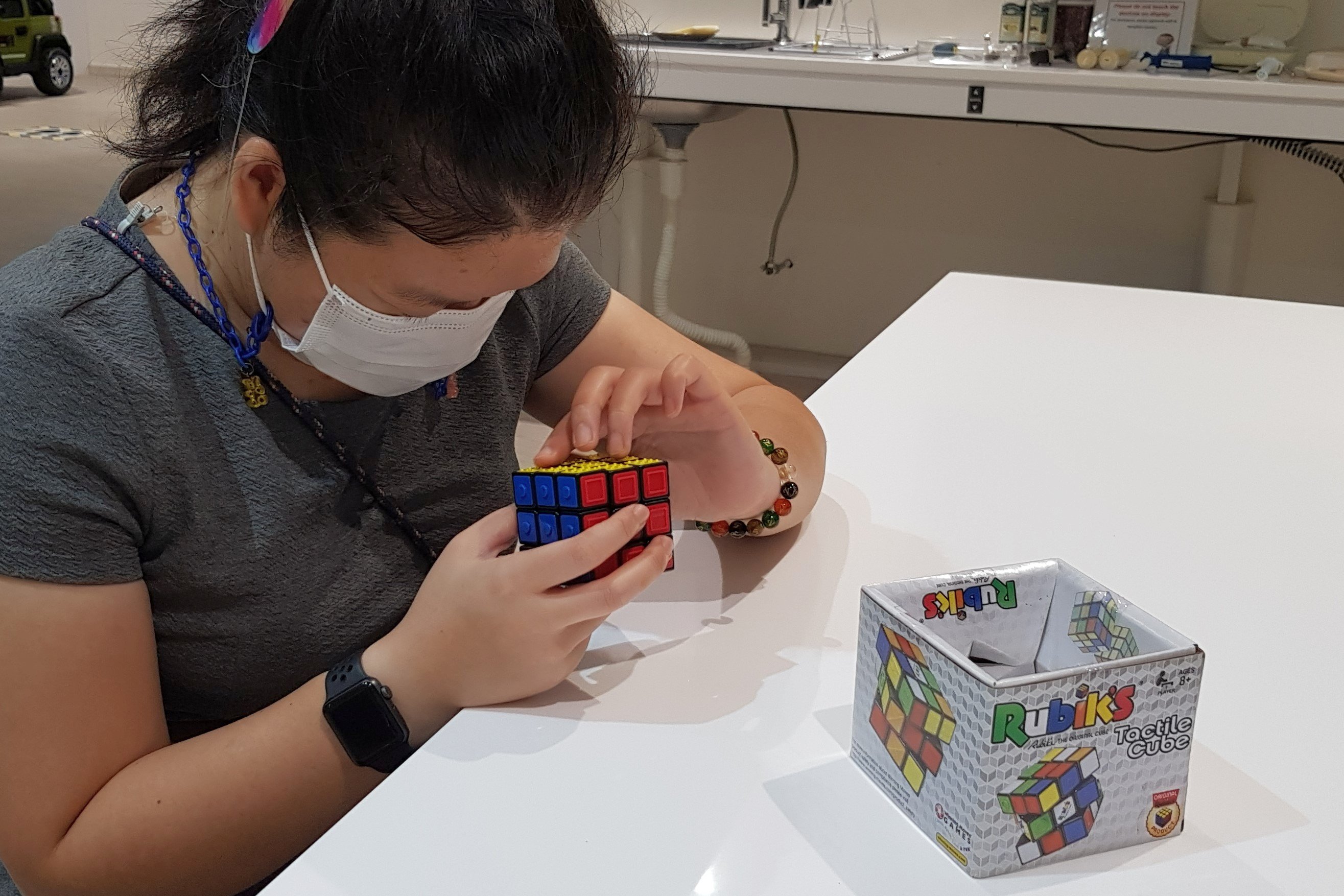 -Siew Ling fingering the Rubik’s Tactile Cube which is marked with different symbols to represent the six colours of the cube.