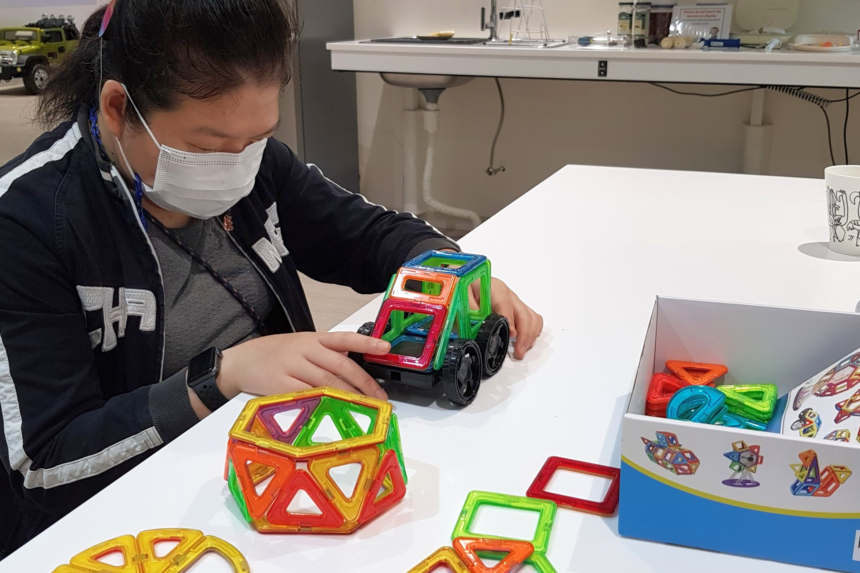 Siew Ling playing with a mini-car she made out of colourful tactile magnetic shapes.