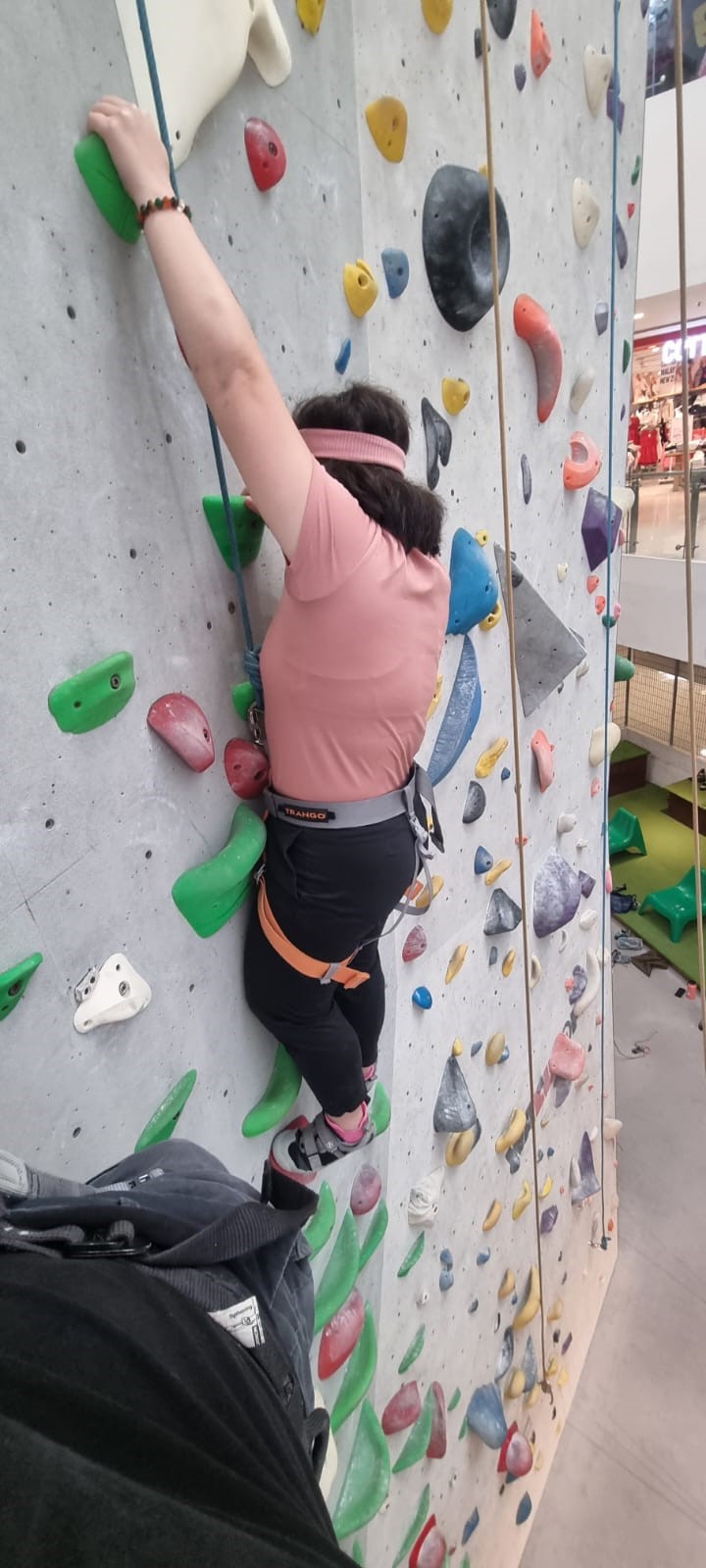 Siew Ling gripping the handholds as she scaled a rock wall in an indoor mall