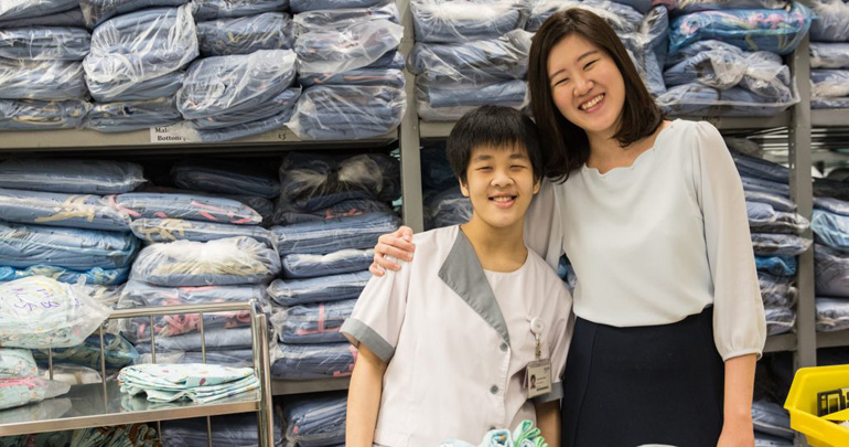 An intern participant posing for a photo with her supervisor in the NUH laundry room