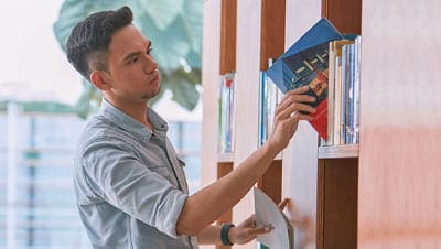 A young man looking for information amongst various books