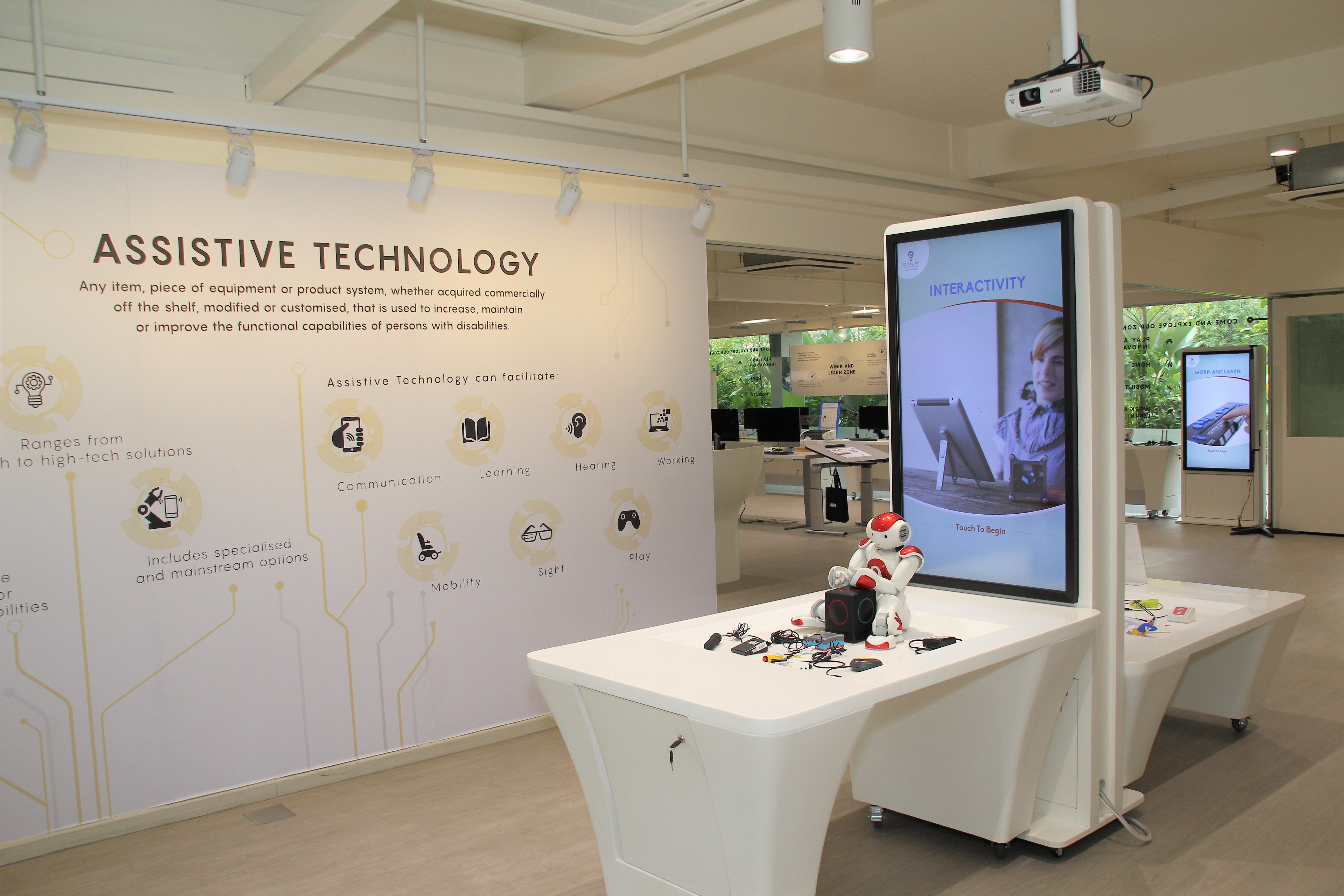 Interior of Tech Able showing digital screens and some assistive technology devices on display like a robot for self-exploration.