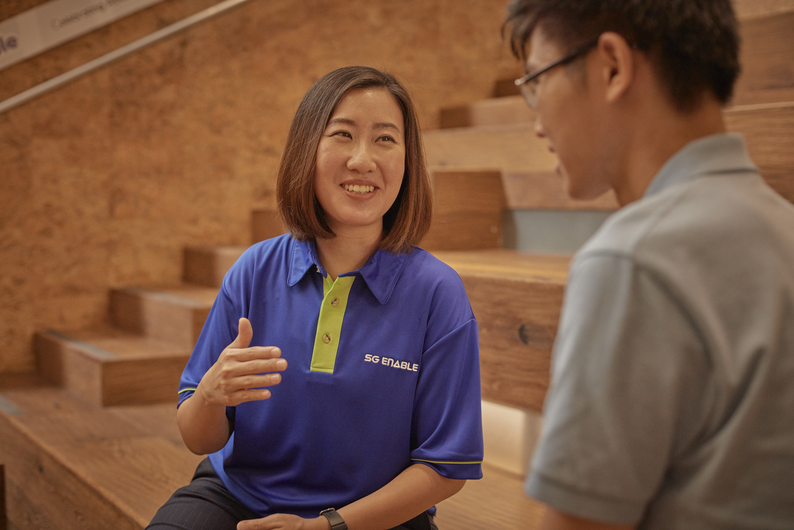 Woman in SG Enable t-shirt converses with the man sitting opposite her.