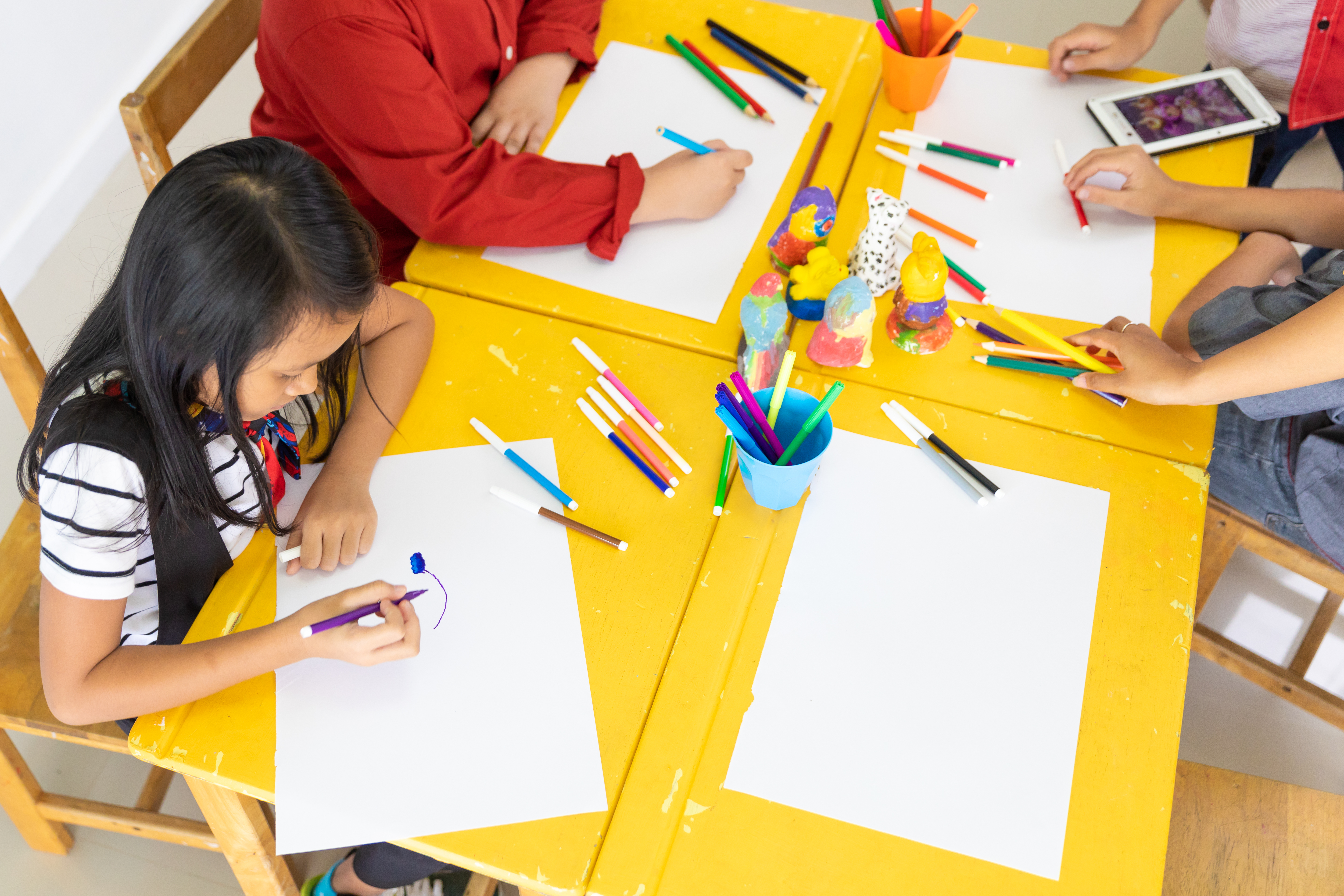 Around 150 children with special needs and their families are expected to benefit from increased subsidies on Special Student Care Services. A group of children seated at a table to draw at a student care centre.