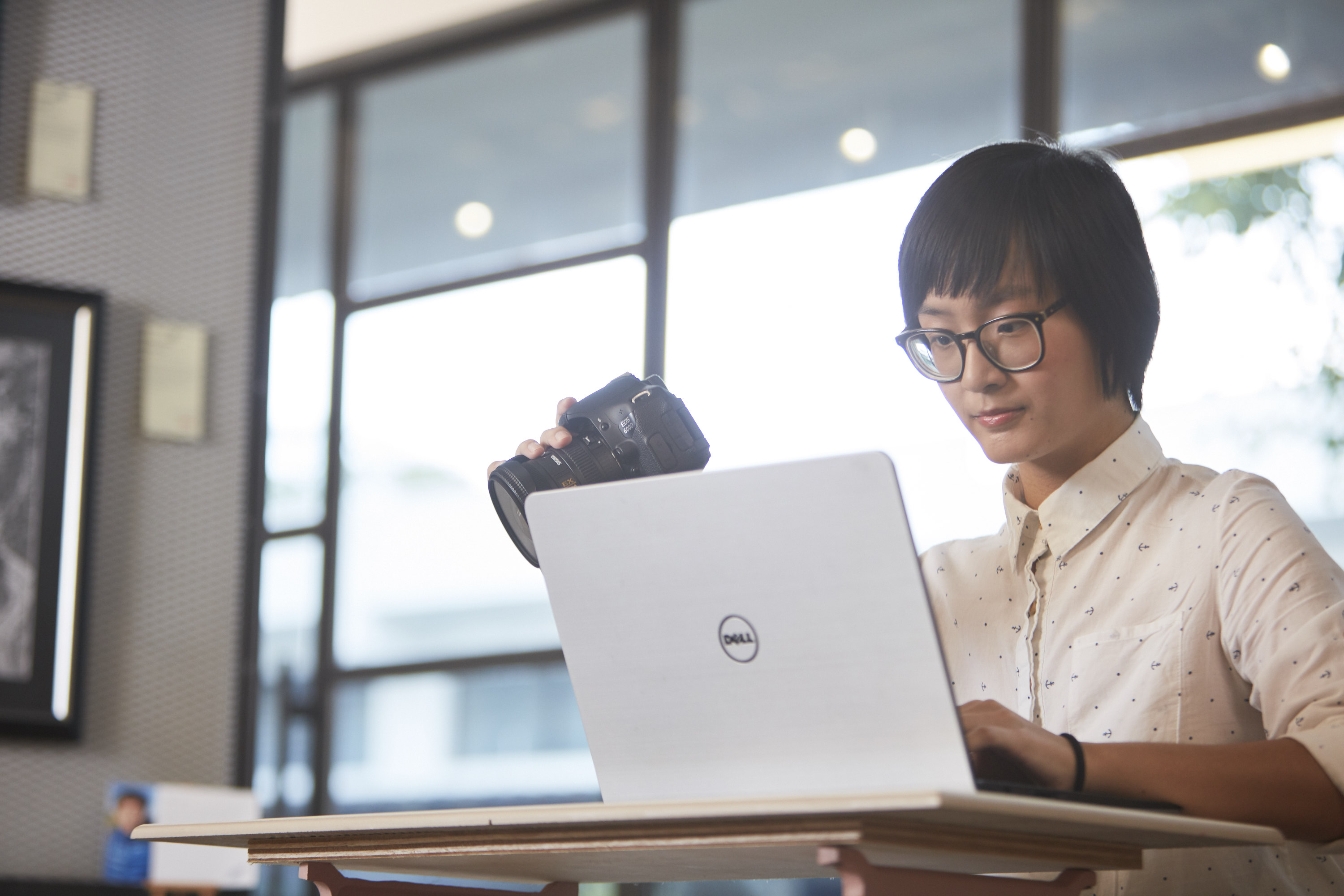 Image of a girl holding on to her camera while using her laptop