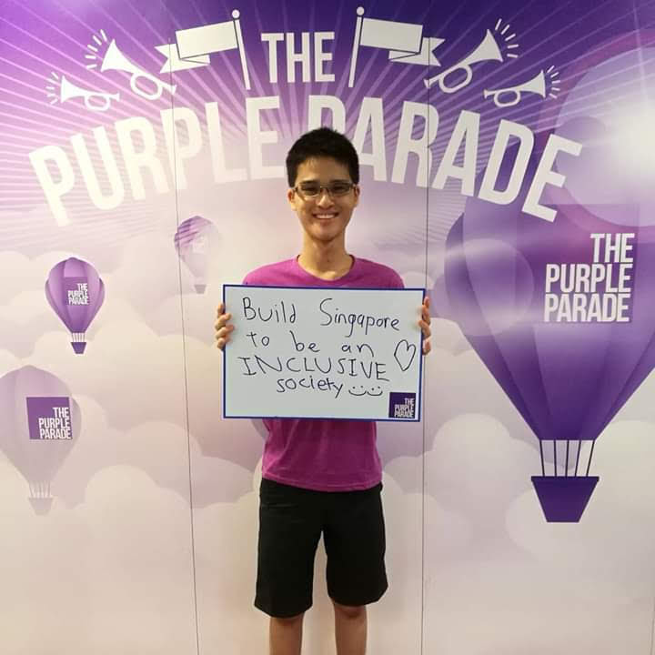 Wesley, advocating for inclusivity at the Purple Parade, an annual event to support inclusion and celebrate abilities of persons with special needs. The photo shows Wesley in a purple t-shirt holding up a sign that says “Build Singapore to be an INCLUSIVE society ” in front of a backdrop with “The Purple Parade” written several times on it.