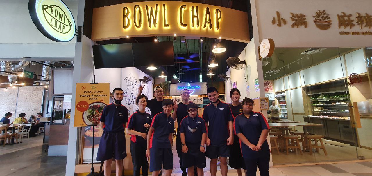 Students from Fernvale Gardens School taking a photo with staff from Bowlchap at storefront.