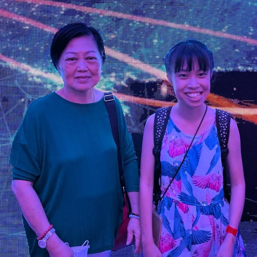 Janevi smiling widely in a floral dress next to an individual